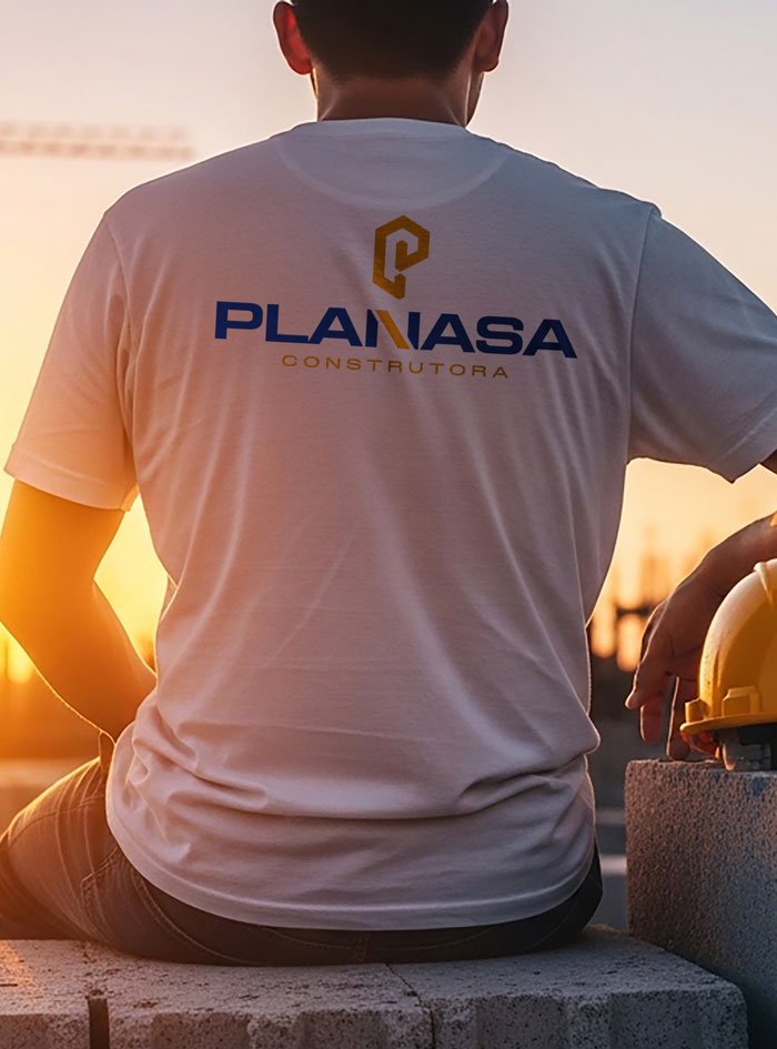 Profissional da equipe Planasa Construtora com camiseta da marca em obra